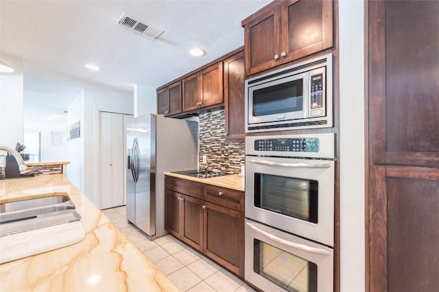 13113 Mansfield Dr, Austin, TX 78732 - kitchen with stainless steel appliances, tasteful backsplash, light tile patterned flooring, recessed lighting, and light stone countertops