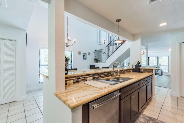 kitchen with light tile patterned floors, hanging light fixtures, stainless steel dishwasher, and an inviting chandelier