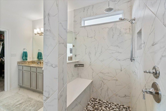 bathroom featuring marble finish floor, a marble finish shower, a walk in closet, and vanity