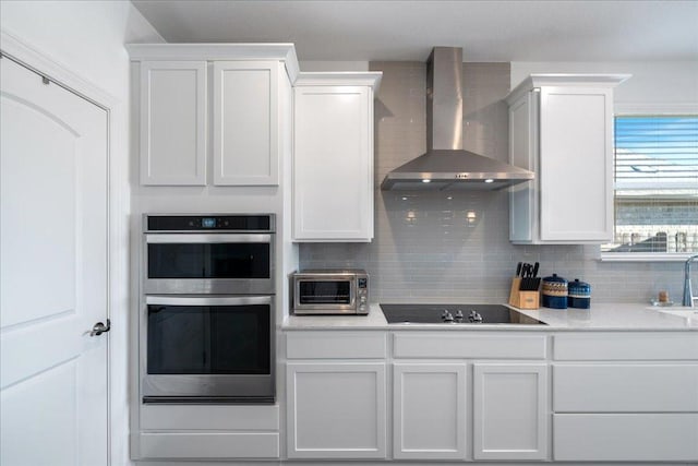 185 Slenderleaf Dr, Marble Falls, TX 78654 - kitchen featuring wall chimney range hood, stainless steel double oven, black electric stovetop, a sink, and decorative backsplash