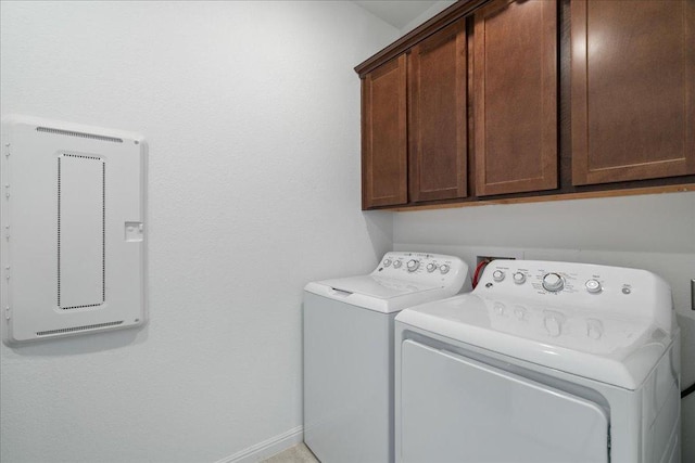 washroom with baseboards, cabinet space, and washer and dryer