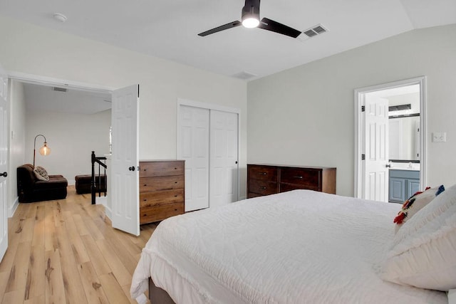 bedroom with a closet, visible vents, light wood-style flooring, a ceiling fan, and ensuite bath