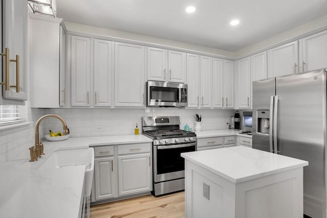 kitchen with light wood-style floors, tasteful backsplash, stainless steel appliances, and a sink