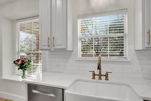 kitchen featuring a sink, white cabinets, light countertops, stainless steel dishwasher, and decorative backsplash