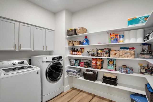 laundry area with light wood-type flooring, washing machine and dryer, and cabinet space