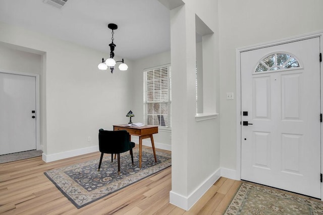 foyer with light wood-type flooring, visible vents, baseboards, and an inviting chandelier