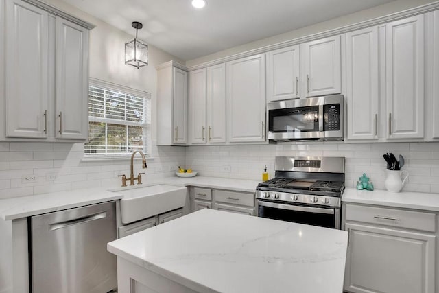 kitchen featuring a kitchen island, a sink, appliances with stainless steel finishes, tasteful backsplash, and pendant lighting