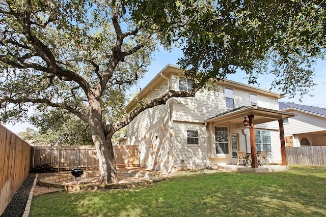 back of property with a fenced backyard, a patio, and a lawn