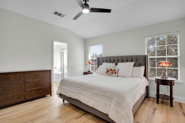 bedroom featuring vaulted ceiling, ensuite bathroom, visible vents, and light wood-style floors