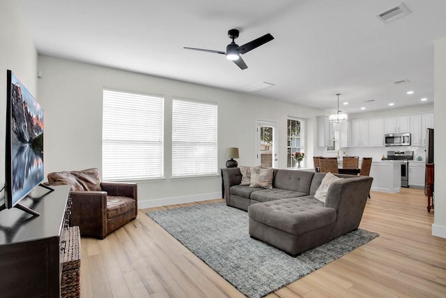 living area with baseboards, visible vents, ceiling fan with notable chandelier, light wood-style floors, and recessed lighting