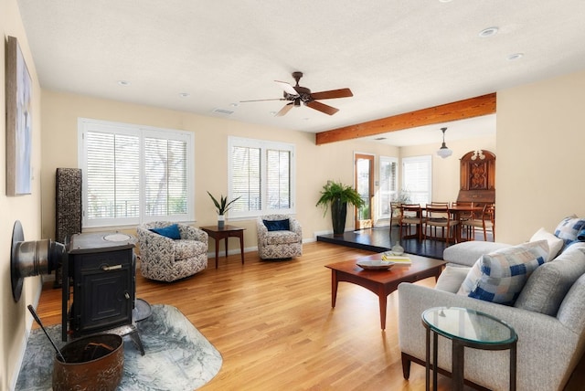 living area with a textured ceiling, visible vents, baseboards, light wood-type flooring, and beam ceiling