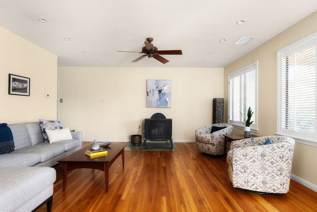 living room featuring a wood stove, visible vents, plenty of natural light, and wood finished floors