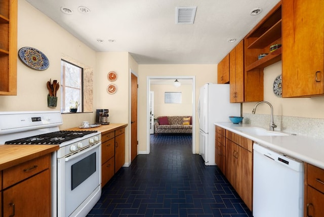 kitchen with brown cabinets, open shelves, visible vents, a sink, and white appliances