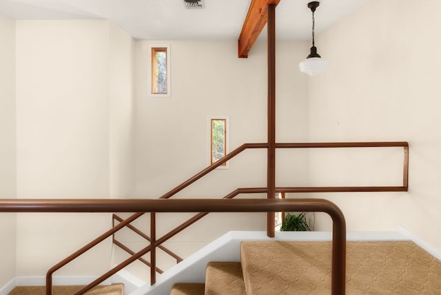 stairway with visible vents, beam ceiling, and baseboards