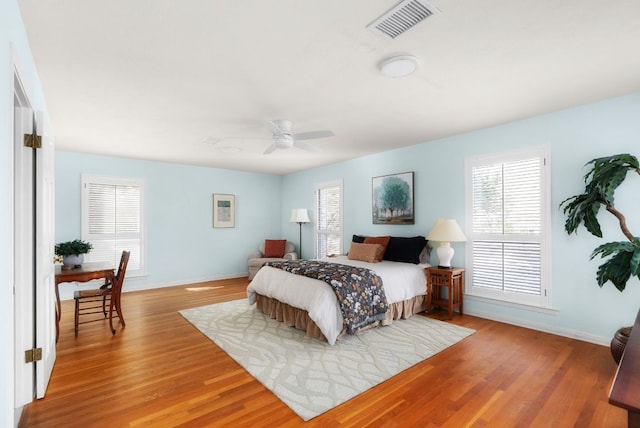 bedroom featuring ceiling fan, wood finished floors, visible vents, and baseboards