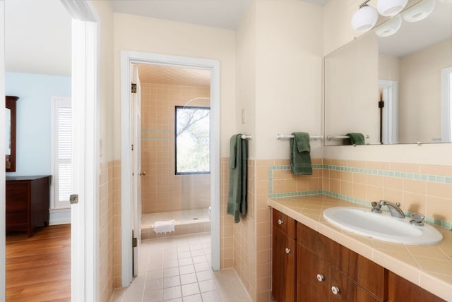 bathroom featuring a stall shower, tile patterned flooring, tile walls, and vanity