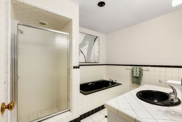 603 N Tumbleweed Trl, Austin, TX 78733 - full bathroom with a shower stall, tile walls, a garden tub, tile patterned flooring, and a wainscoted wall