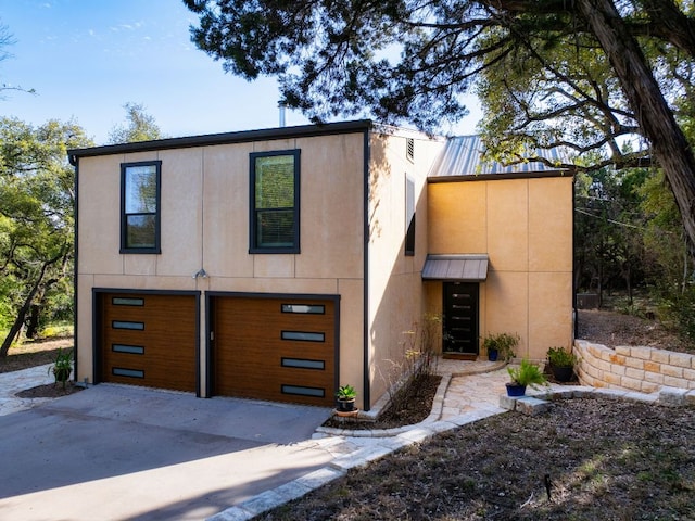 view of front of home with a garage, concrete driveway, and stucco siding