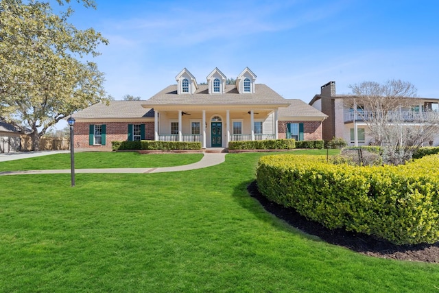 view of front of house featuring ceiling fan, a front lawn, and brick siding