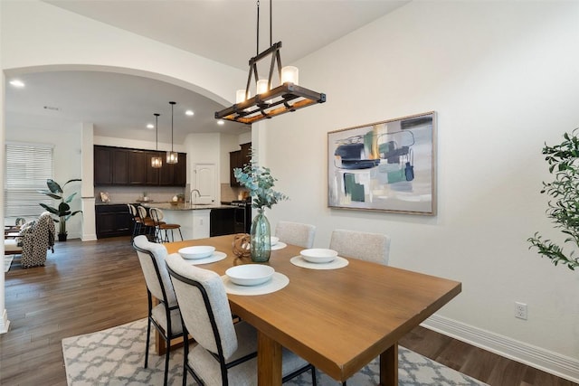 dining room featuring baseboards, dark wood finished floors, arched walkways, and recessed lighting