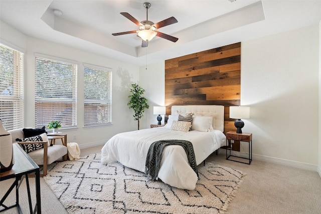 bedroom featuring multiple windows, a tray ceiling, and carpet flooring