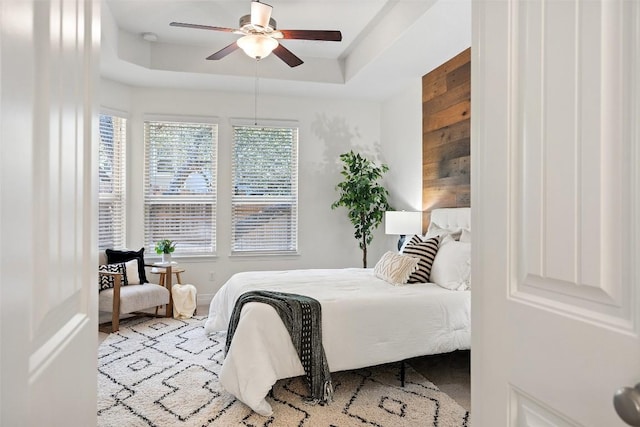 bedroom with a raised ceiling and a ceiling fan