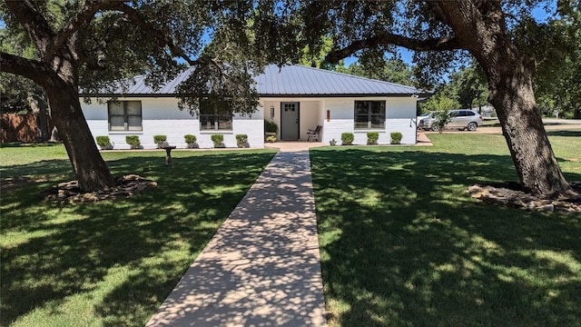 view of front of property with a front yard, brick siding, and metal roof