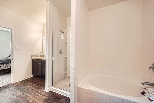 ensuite bathroom featuring connected bathroom, a garden tub, a stall shower, wood finished floors, and vanity