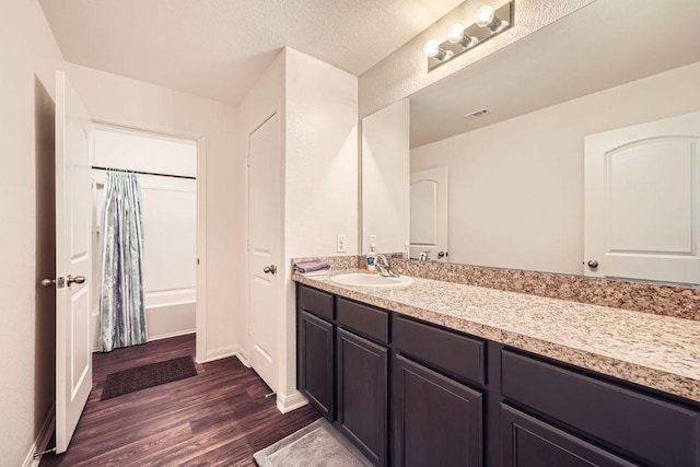 full bath with visible vents, baseboards, vanity, wood finished floors, and a textured ceiling