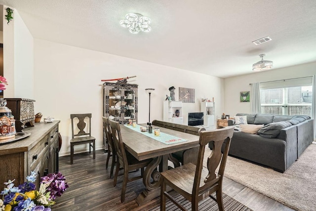 dining area featuring visible vents, baseboards, a textured ceiling, and dark wood-style floors