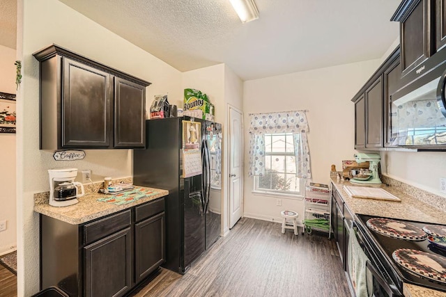 kitchen featuring wood finished floors, black appliances, light countertops, dark brown cabinets, and a textured ceiling