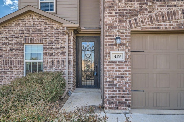 property entrance featuring a garage and brick siding