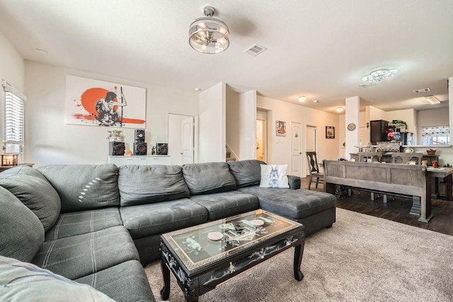 living area with visible vents, plenty of natural light, wood finished floors, and stairway