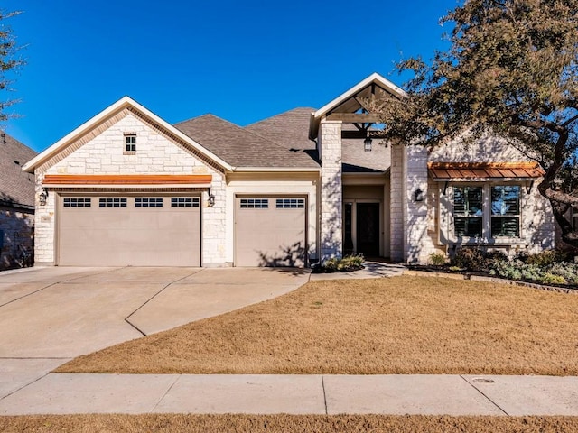 view of front of home featuring a garage, concrete driveway, a shingled roof, and stone siding