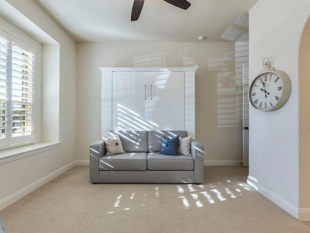 living area with carpet floors, baseboards, and a ceiling fan