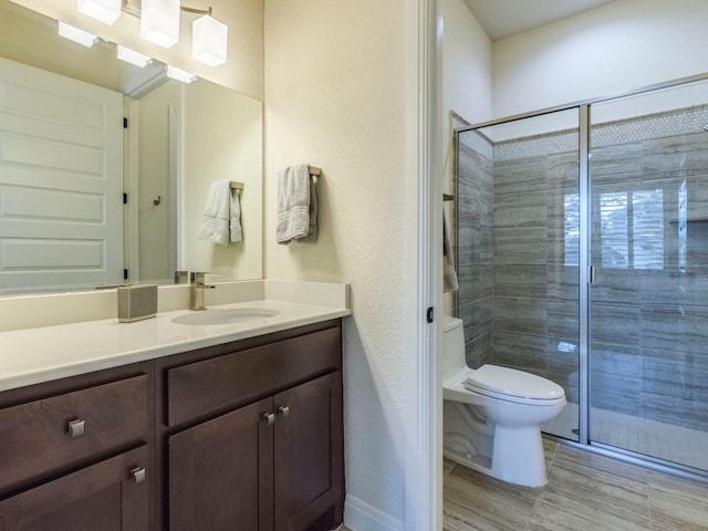 bathroom featuring toilet, a stall shower, and vanity