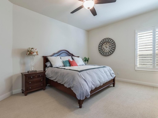 bedroom featuring light carpet, a ceiling fan, and baseboards