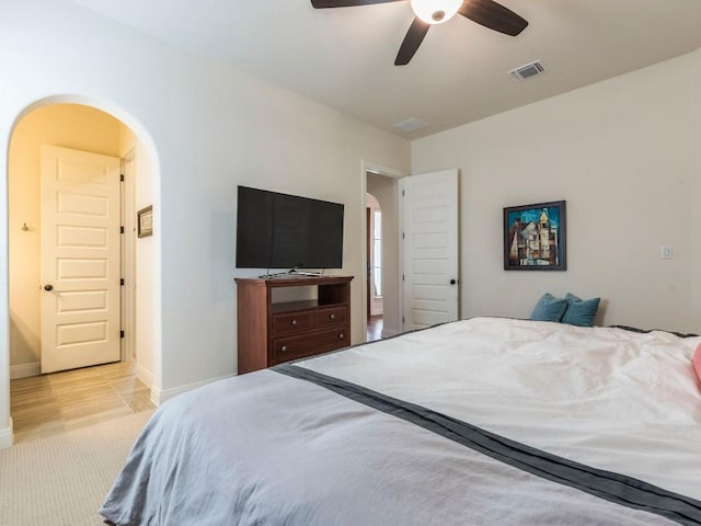 bedroom with arched walkways, visible vents, a ceiling fan, light carpet, and baseboards