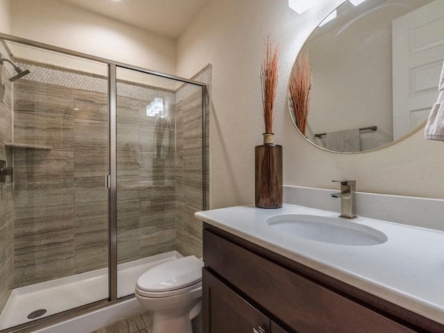 bathroom with a shower stall, toilet, and vanity