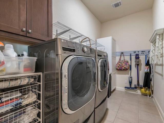 washroom with cabinet space, baseboards, visible vents, washer and dryer, and light tile patterned flooring