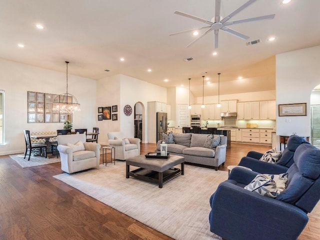 living area with light wood-style flooring, visible vents, and arched walkways