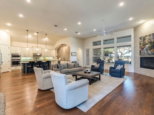 living area with dark wood-style floors, recessed lighting, a large fireplace, and visible vents