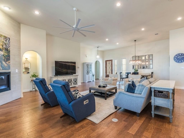 living room featuring arched walkways, a fireplace, recessed lighting, and wood finished floors