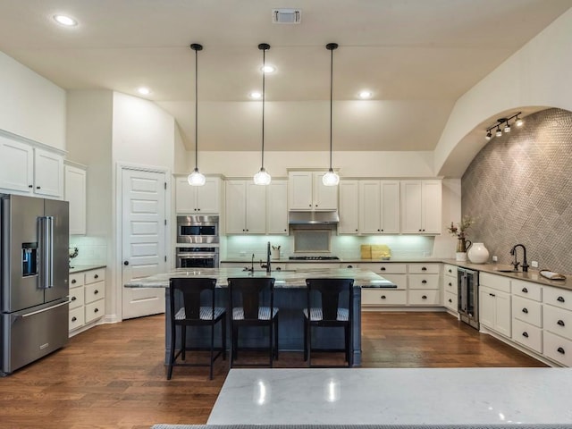 kitchen with dark wood finished floors, stainless steel appliances, visible vents, beverage cooler, and under cabinet range hood