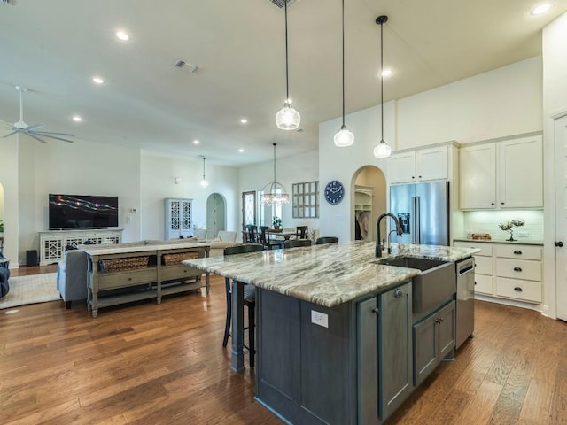 kitchen with arched walkways, dark wood-style flooring, a sink, open floor plan, and appliances with stainless steel finishes