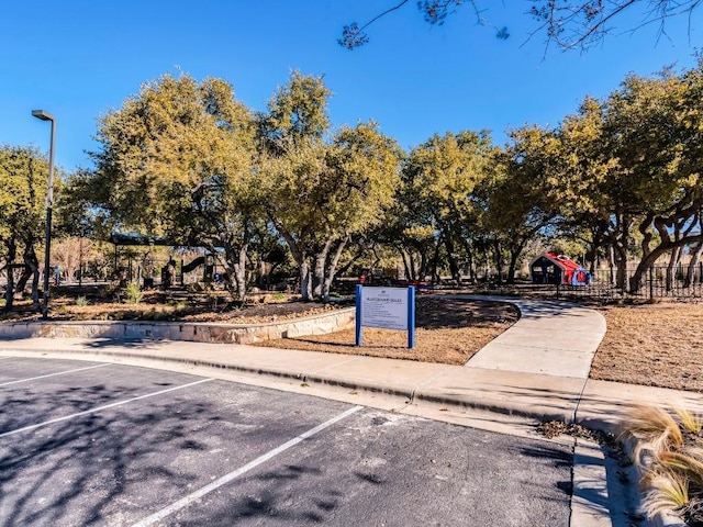 view of community with uncovered parking and playground community