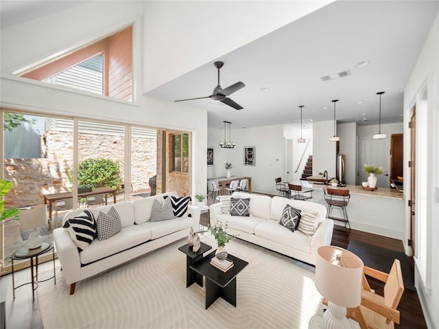 living area with ceiling fan, visible vents, stairway, and wood finished floors