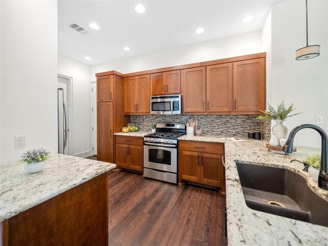 kitchen with visible vents, brown cabinetry, dark wood-style flooring, stainless steel appliances, and a sink