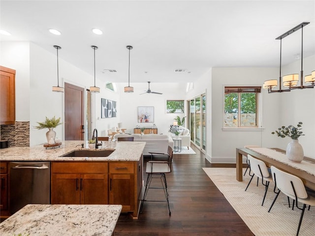 kitchen featuring dark wood finished floors, tasteful backsplash, recessed lighting, a sink, and light stone countertops