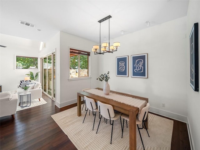 dining area featuring dark wood-style floors, an inviting chandelier, visible vents, and baseboards